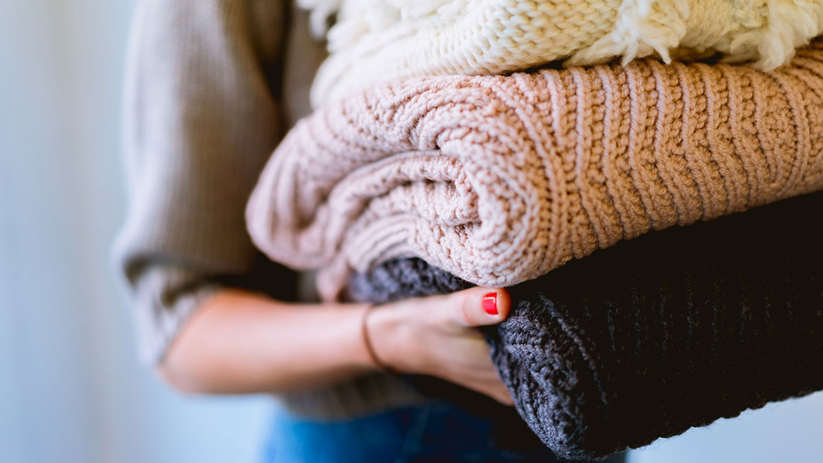 Woman holding pile of knit blankets